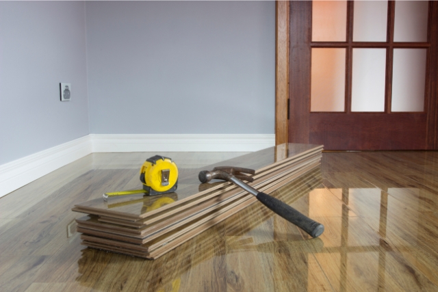 Flooring Repair with hammer and measuring tape and hardwood planks